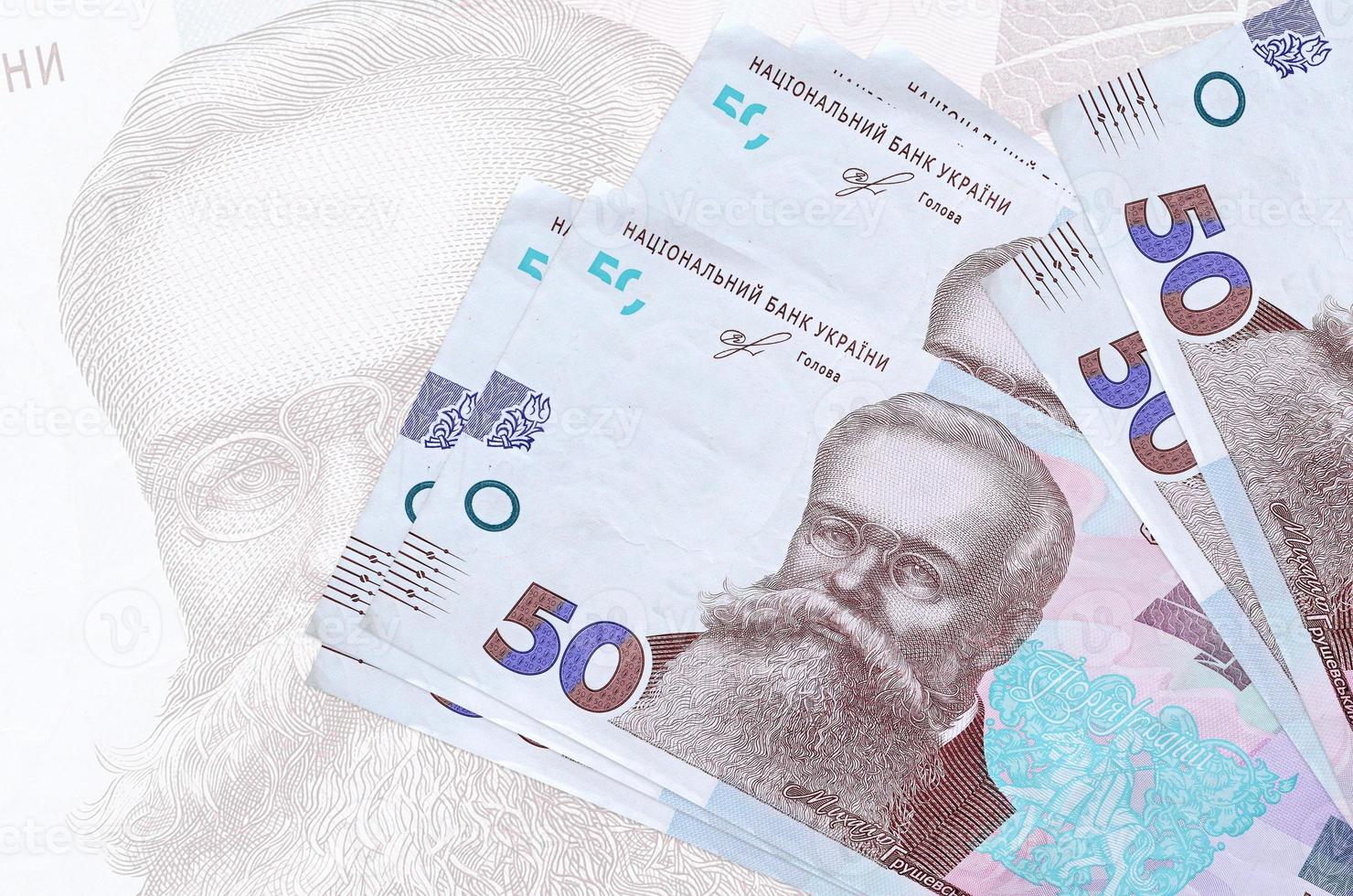 Notas de 50 hryvnias ucranianas estão na pilha no fundo da grande nota semitransparente. apresentação abstrata da moeda nacional foto