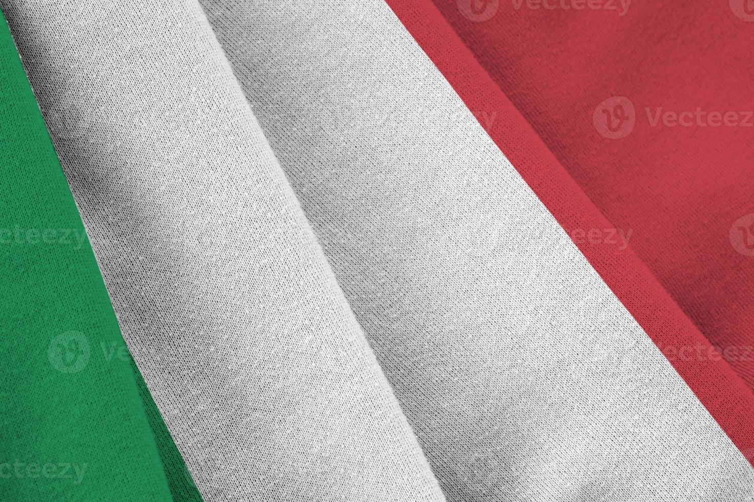 bandeira da itália com grandes dobras acenando de perto sob a luz do estúdio dentro de casa. os símbolos oficiais e cores no banner foto