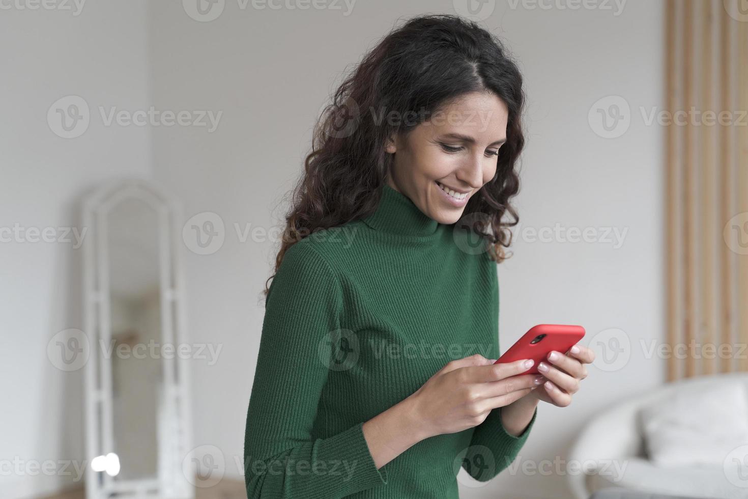 jovem espanhola feliz usando telefone celular e conversando com amigos, enviando sms no smartphone foto