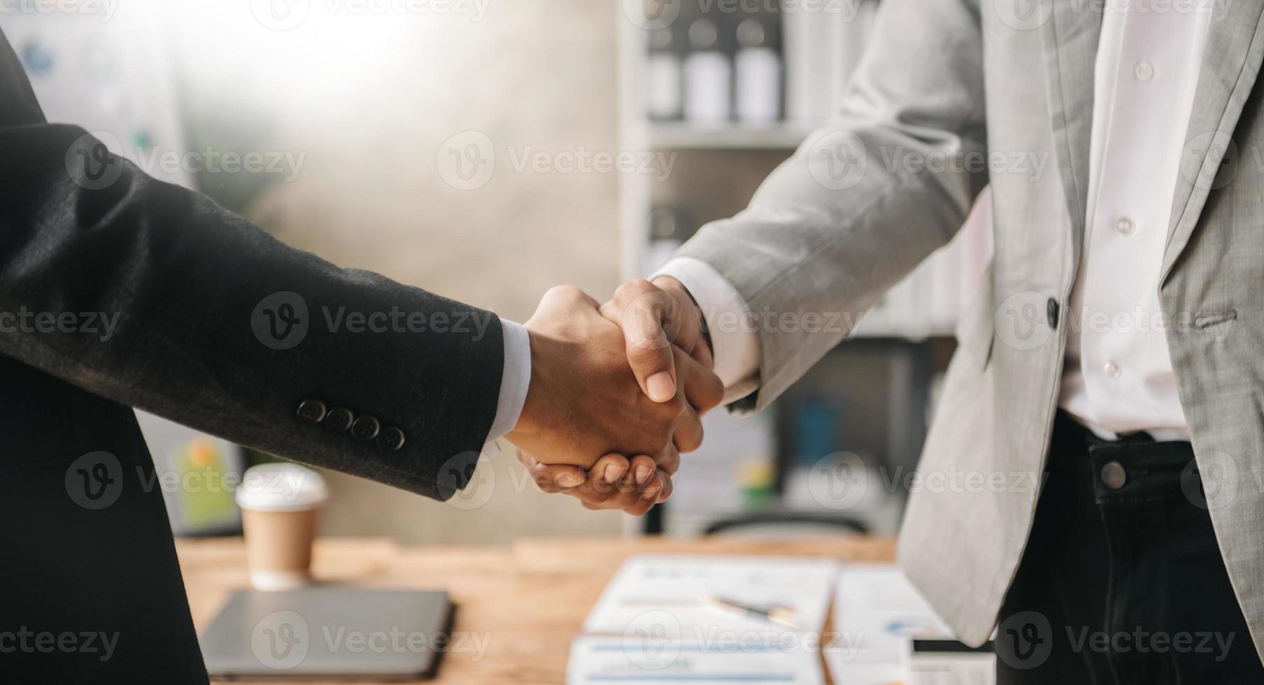 dois homens de negócios confiantes apertando as mãos durante uma reunião no escritório, sucesso, negociação, saudação e parceiro na luz do sol foto