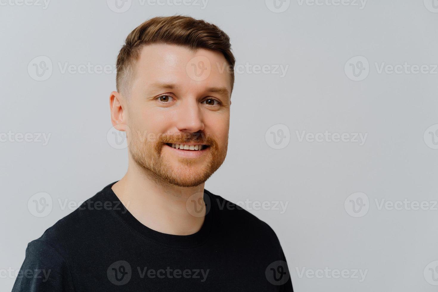 homem bonito com barba sorrindo para a câmera e expressando positividade foto