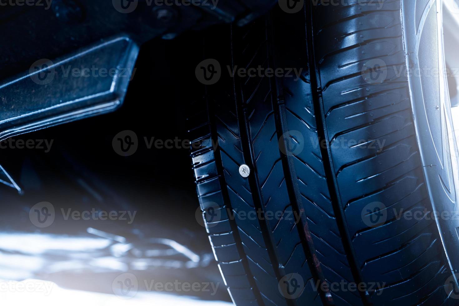 parafuso ou prego furou o pneu de borracha preta do carro. acidente de roda de carro na estrada com pneu furado. dirija com um prego no pneu. remova e repare o prego de metal no pneu do carro. seguro para dirigir com um parafuso no pneu. foto