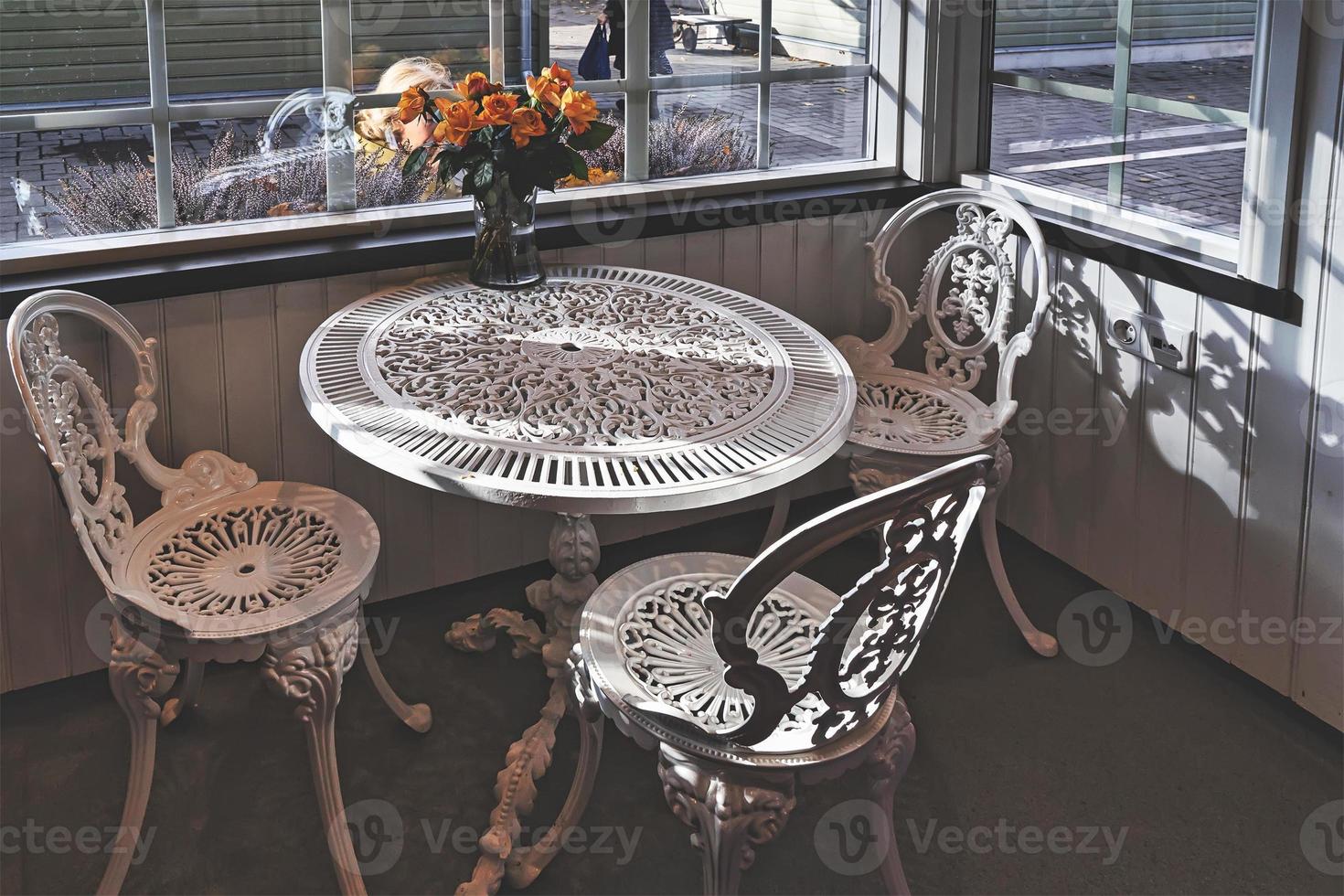 mesa de jardim de ferro forjado vintage vazia e cadeiras no café público dentro de um dia de outono. foto