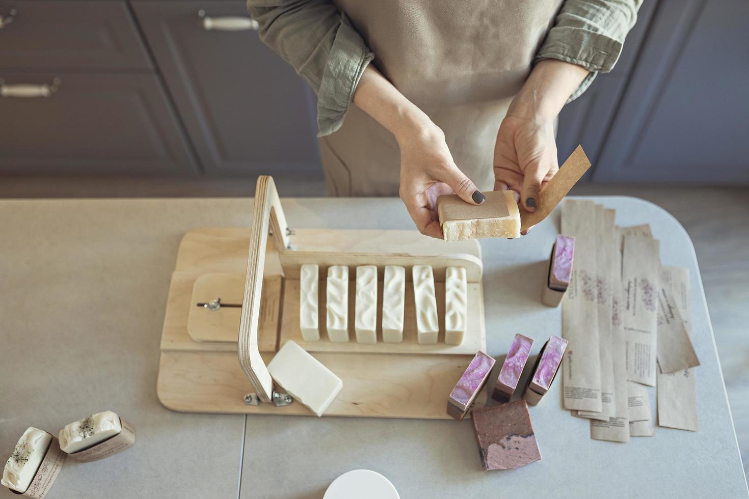 uma garota fabricante de sabão segura um pedaço de sabonete artesanal acabado de fazer em suas mãos. o processo de preparação e embalagem. casa spa. pequena empresa foto