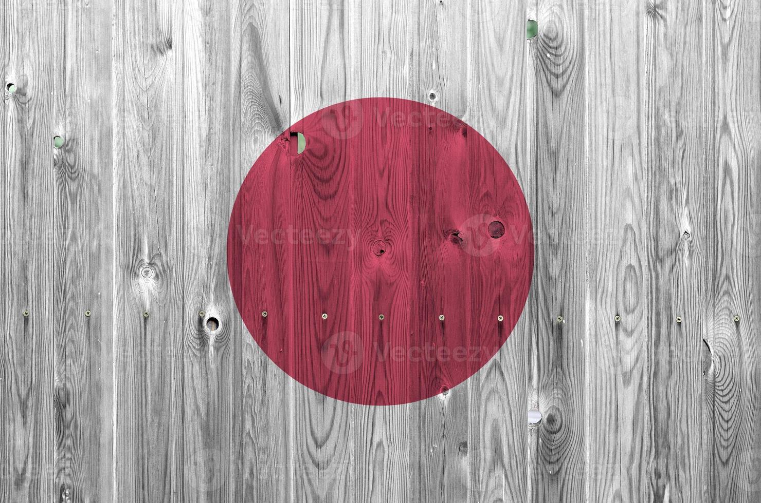 bandeira do japão retratada em cores brilhantes de tinta na parede de madeira velha. banner texturizado em fundo áspero foto