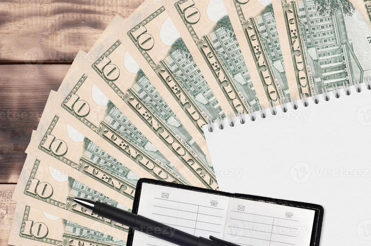 Ventilador de notas de 10 dólares americanos e bloco de notas com livro de contatos e caneta preta. conceito de planejamento financeiro e estratégia de negócios foto