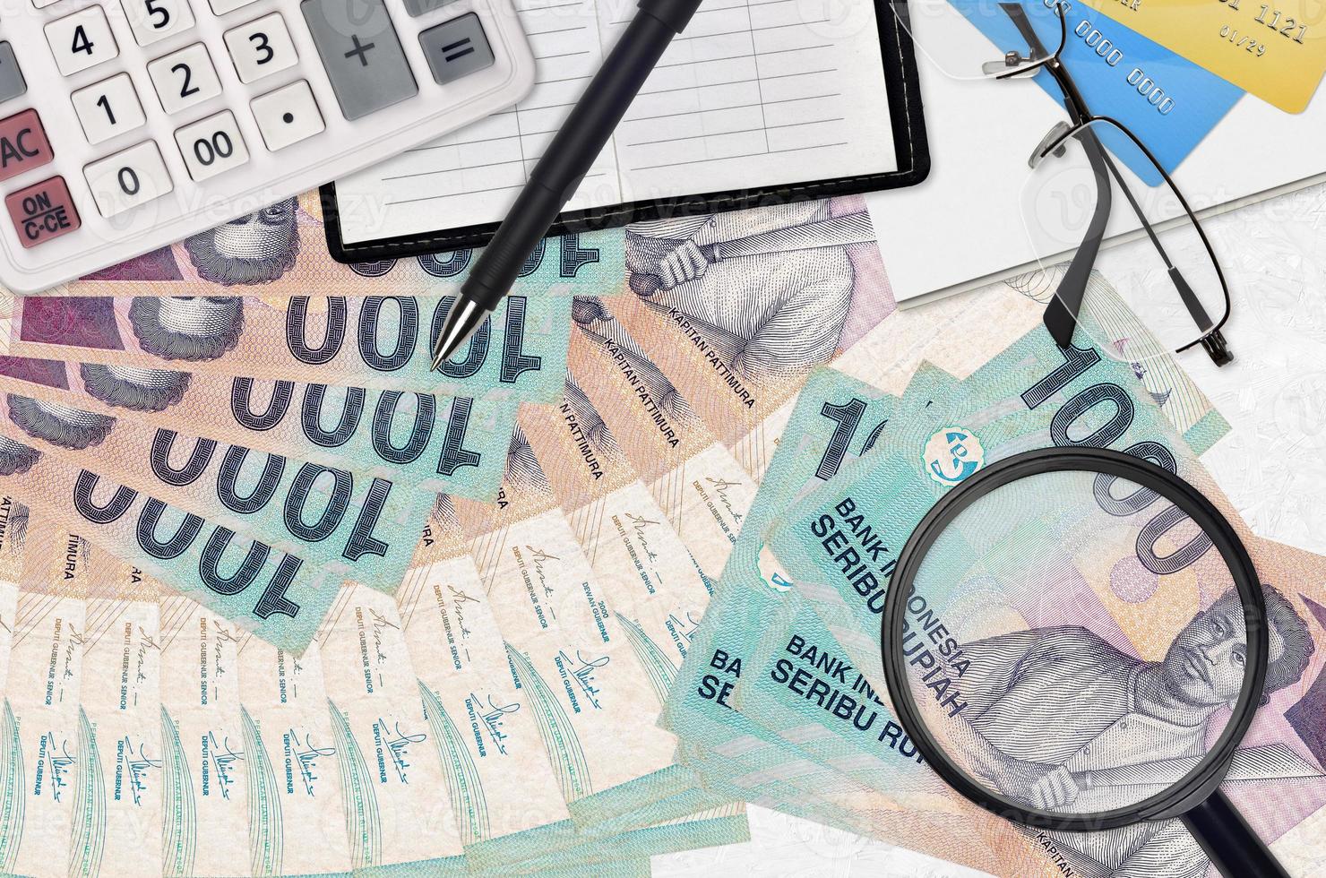Notas de 1000 rupias indonésias e calculadora com óculos e caneta. conceito de temporada de pagamento de impostos ou soluções de investimento. procurando um emprego com salário alto foto