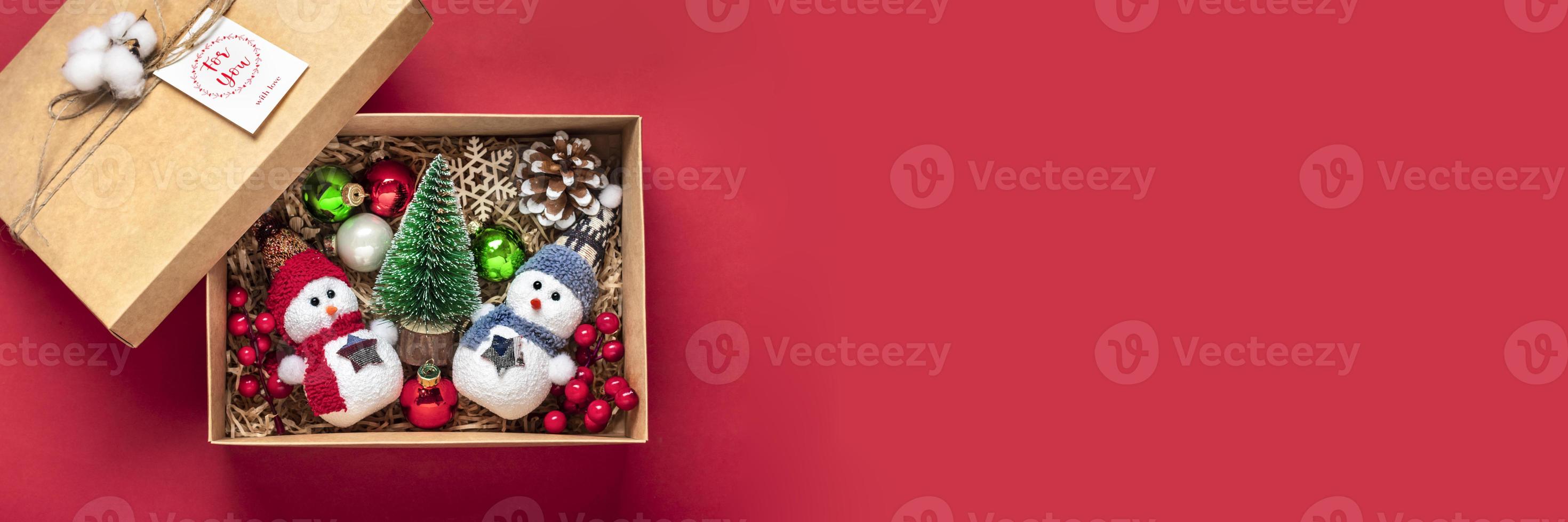 pacote de cuidados artesanais, caixa de presente sazonal com brinquedos, decoração de natal na mesa vermelha cesta ecológica personalizada para família, amigos, menina para 24 de dezembro, natal, dia de ano novo flat lay foto