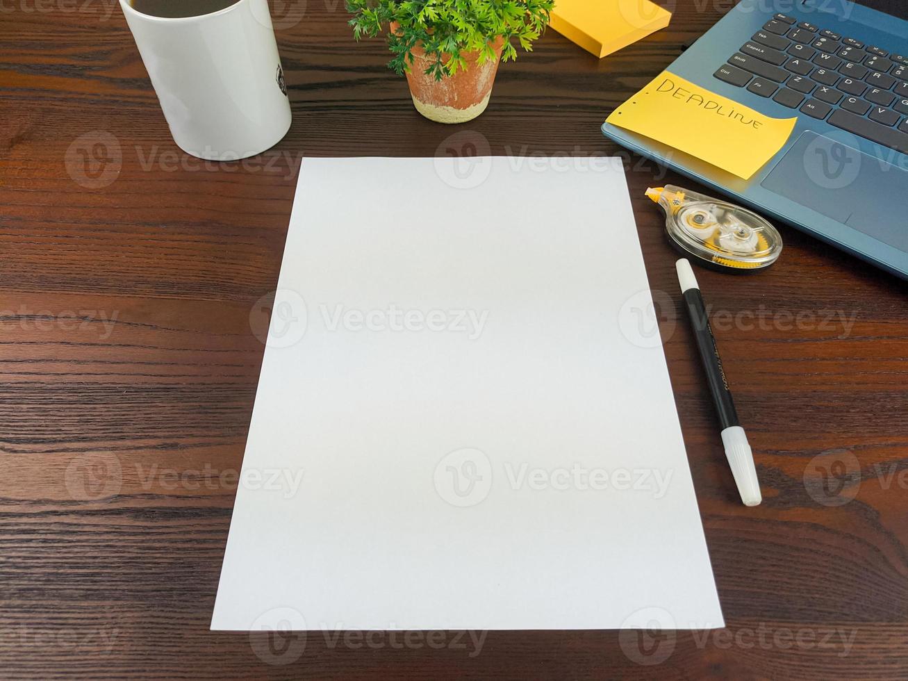 configuração plana, maquete de papel. espaço de trabalho no fundo da mesa de escritório da vista superior. com papel branco em branco, laptops, material de escritório, lápis, folhas verdes e xícaras de café em uma mesa de madeira. foto