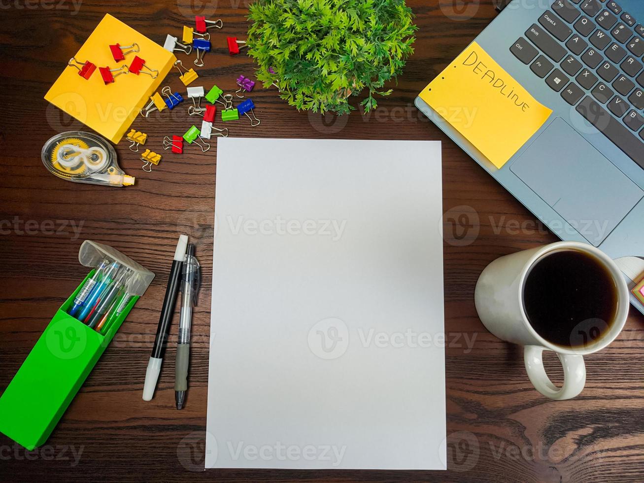 configuração plana, maquete de papel. espaço de trabalho no fundo da mesa de escritório da vista superior. com papel branco em branco, laptops, material de escritório, lápis, folhas verdes e xícaras de café em uma mesa de madeira. foto
