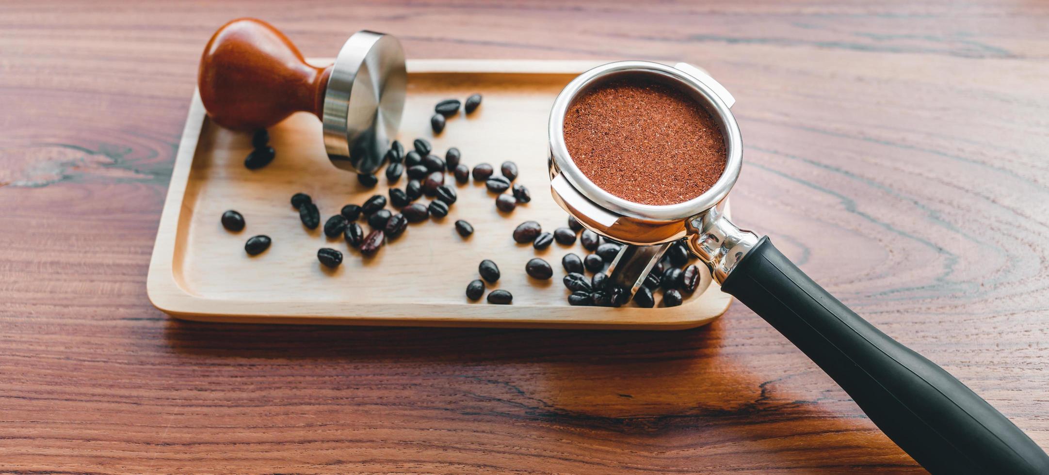 equipamento de adulteração de ferramenta de café barista e café temperado em grãos de café torrados portafilter na mesa de madeira foto
