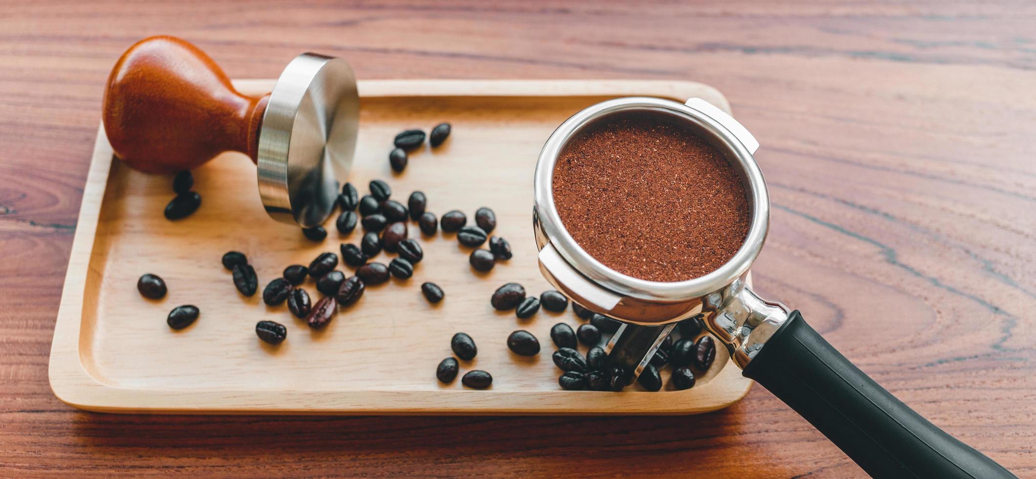 equipamento de adulteração de ferramenta de café barista e café temperado em grãos de café torrados portafilter na mesa de madeira foto