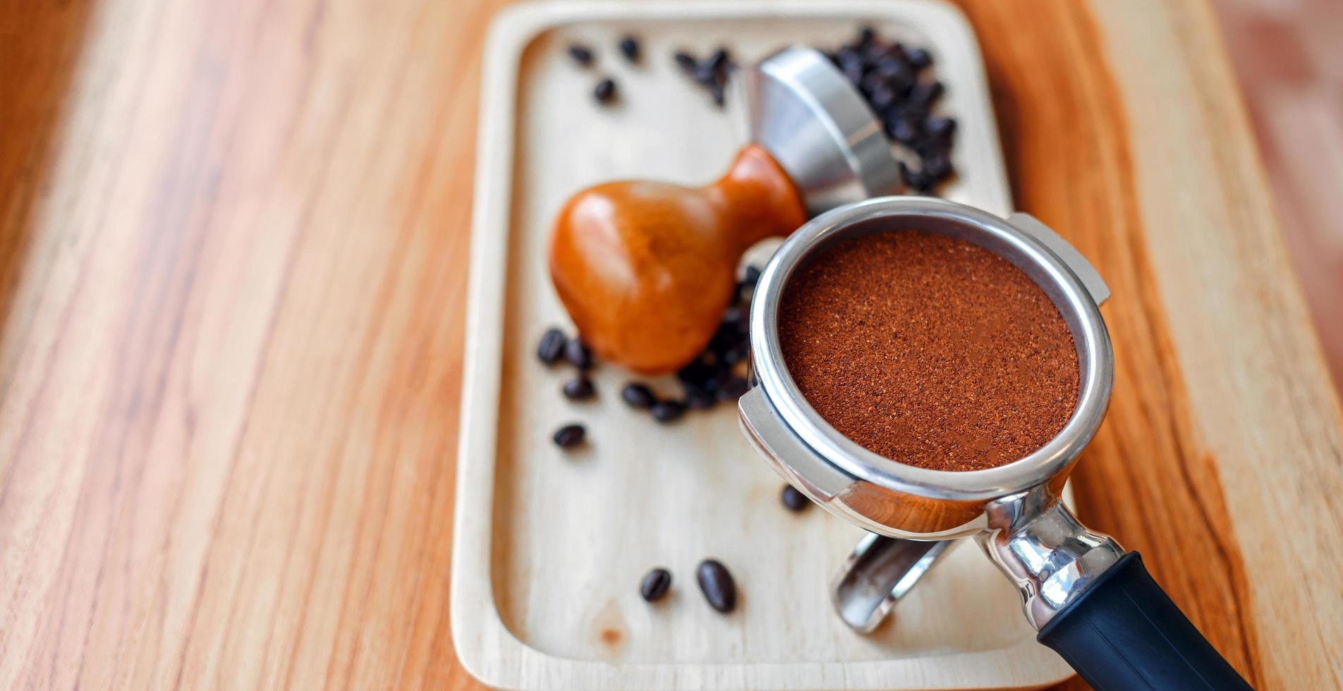 equipamento de adulteração de ferramenta de café barista e café temperado em grãos de café torrados portafilter na mesa de madeira foto