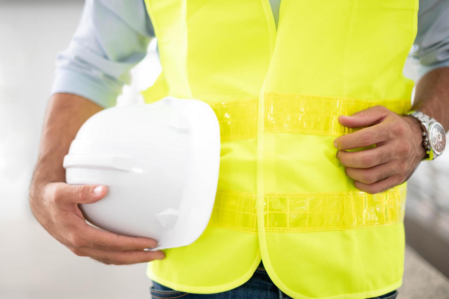 engenheiro segurando capacete vestindo colete amarelo e pronto para a segurança do trabalho no local. foto