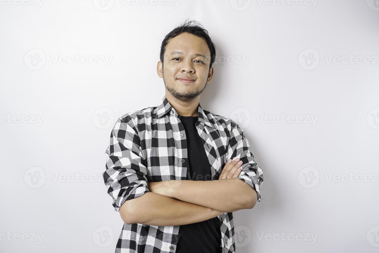 retrato de um homem asiático sorridente confiante vestindo camisa xadrez em pé com os braços cruzados e olhando para a câmera isolada sobre fundo branco foto