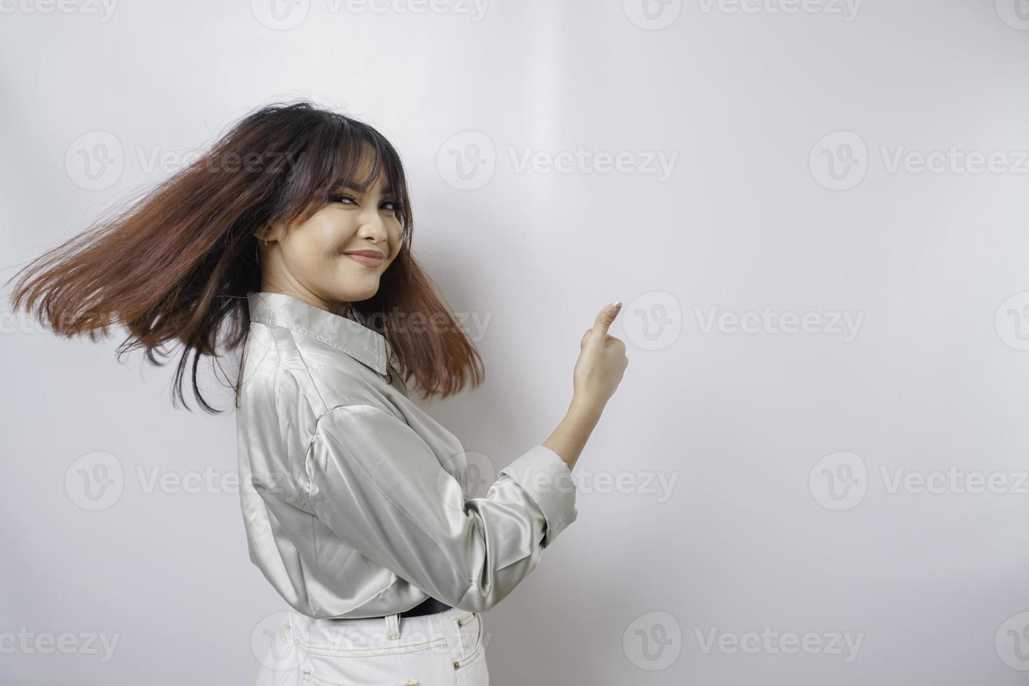 mulher asiática animada vestindo camisa verde sálvia dá polegares para cima gesto de aprovação, isolado pelo fundo branco foto