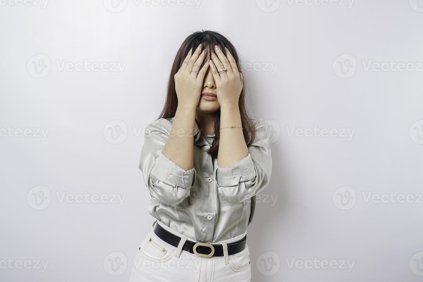 um retrato de uma mulher asiática vestindo uma camisa verde sálvia isolada por um fundo branco parece deprimido foto