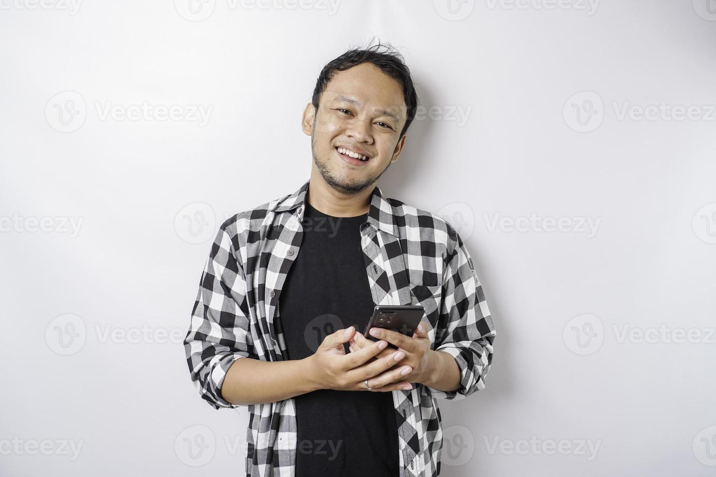 um retrato de um homem asiático feliz está sorrindo enquanto segura seu telefone, isolado pelo fundo branco foto