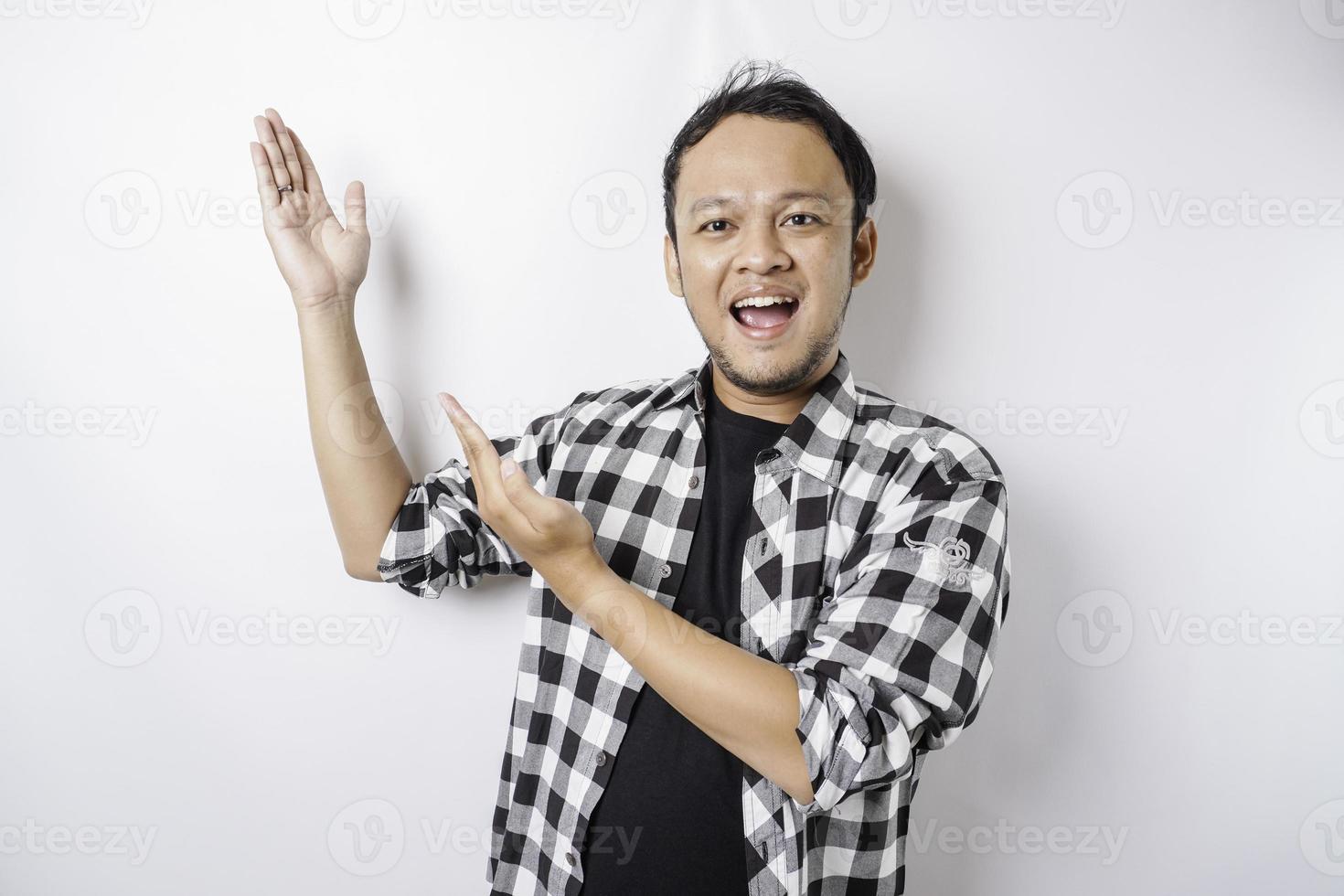 homem asiático sorridente vestindo camisa xadrez está apontando para o espaço da cópia em cima dele, isolado pelo fundo branco foto