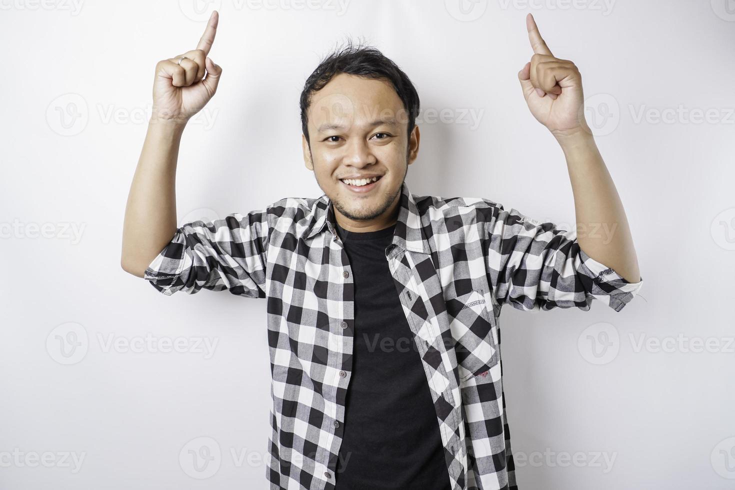 homem asiático sorridente vestindo camisa xadrez está apontando para o espaço da cópia em cima dele, isolado pelo fundo branco foto