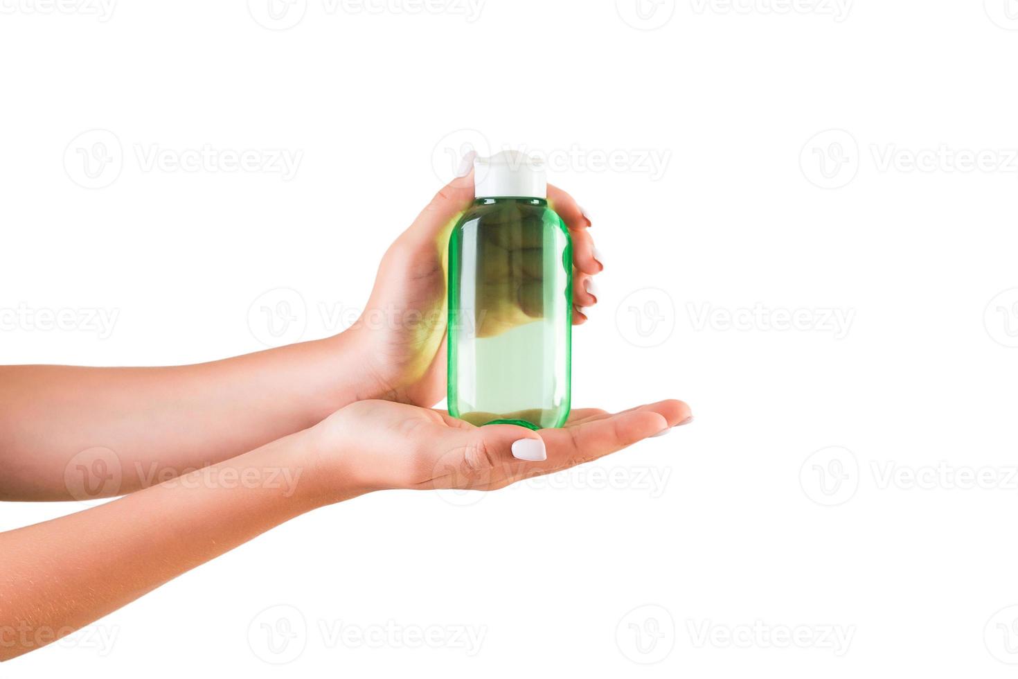 mão feminina segurando o frasco de creme de loção isolado. garota dá produtos cosméticos em fundo branco foto