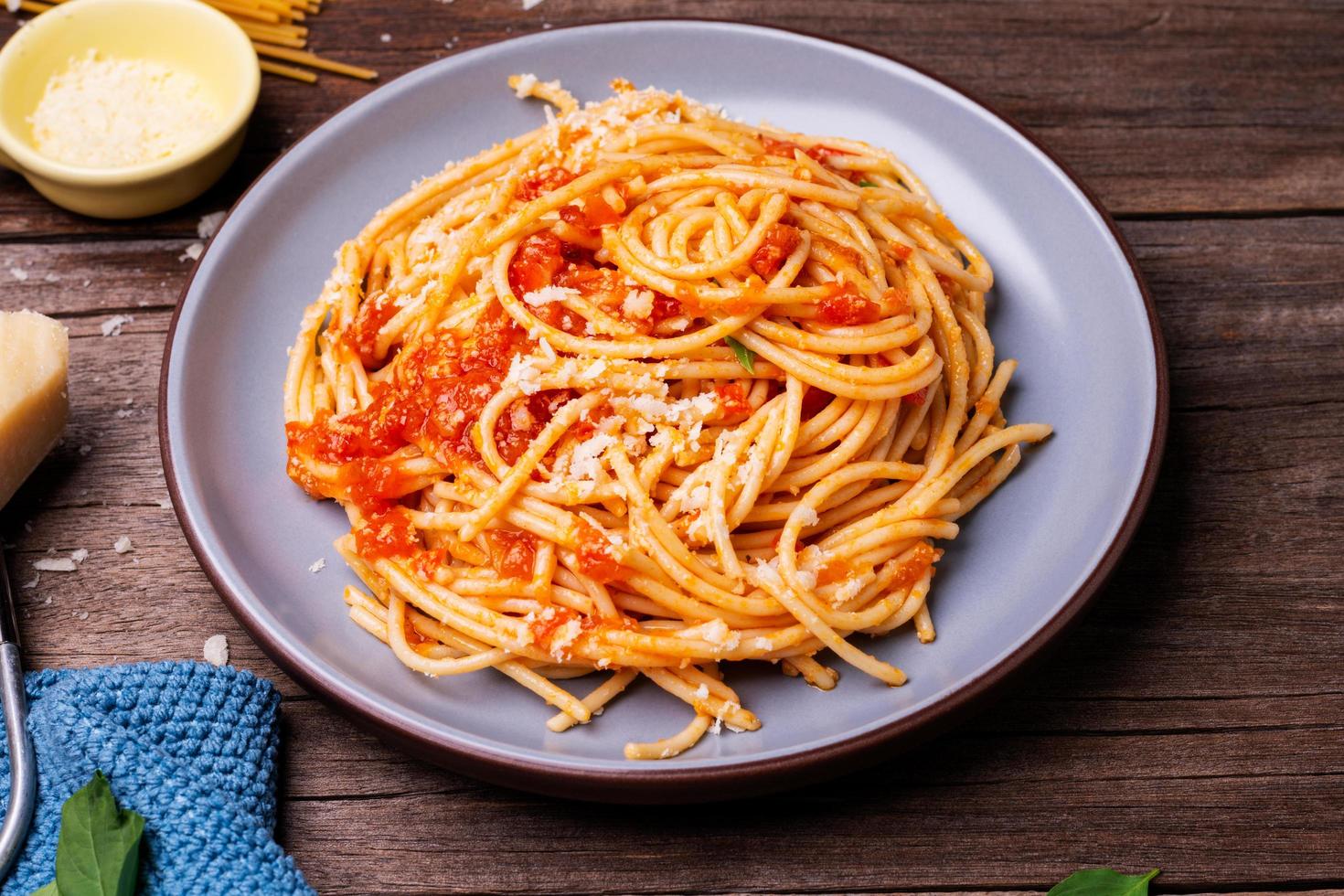 deliciosa massa de queijo espaguete servida em um prato legumes, molho de tomate italiano e especiarias dispostas em uma mesa de madeira, vista superior foto