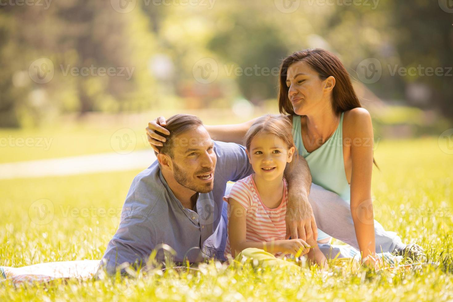 família jovem e feliz com a filhinha se divertindo no parque em um dia ensolarado foto