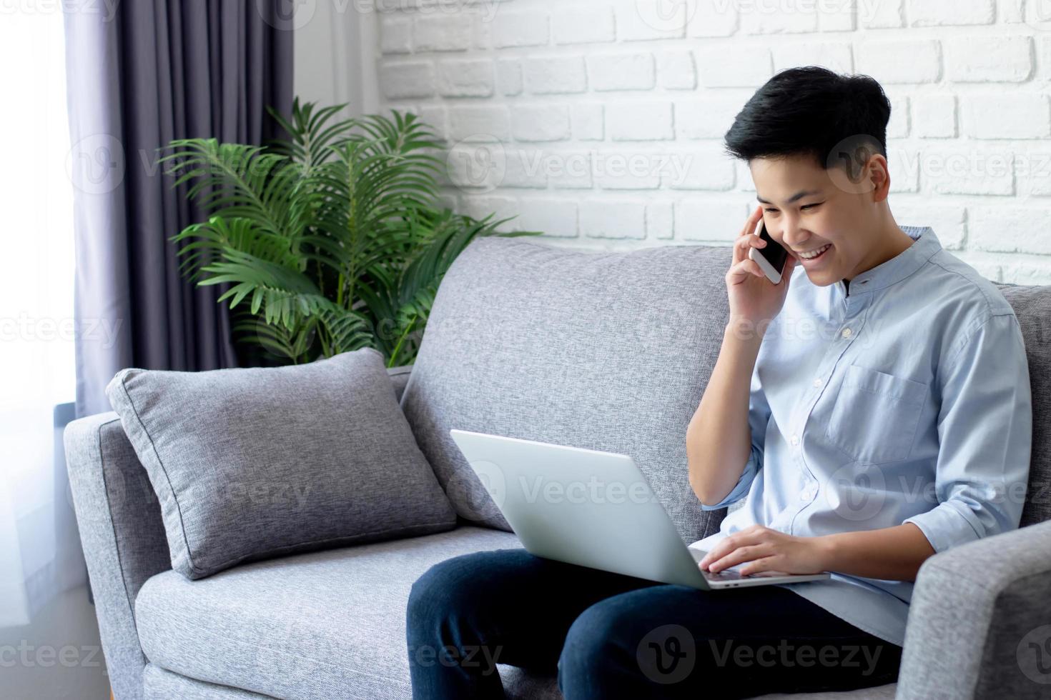 os jovens asiáticos estão satisfeitos com seu sucesso por meio da comunicação usando um smartphone que funciona em casa. tecnologia de conceito foto