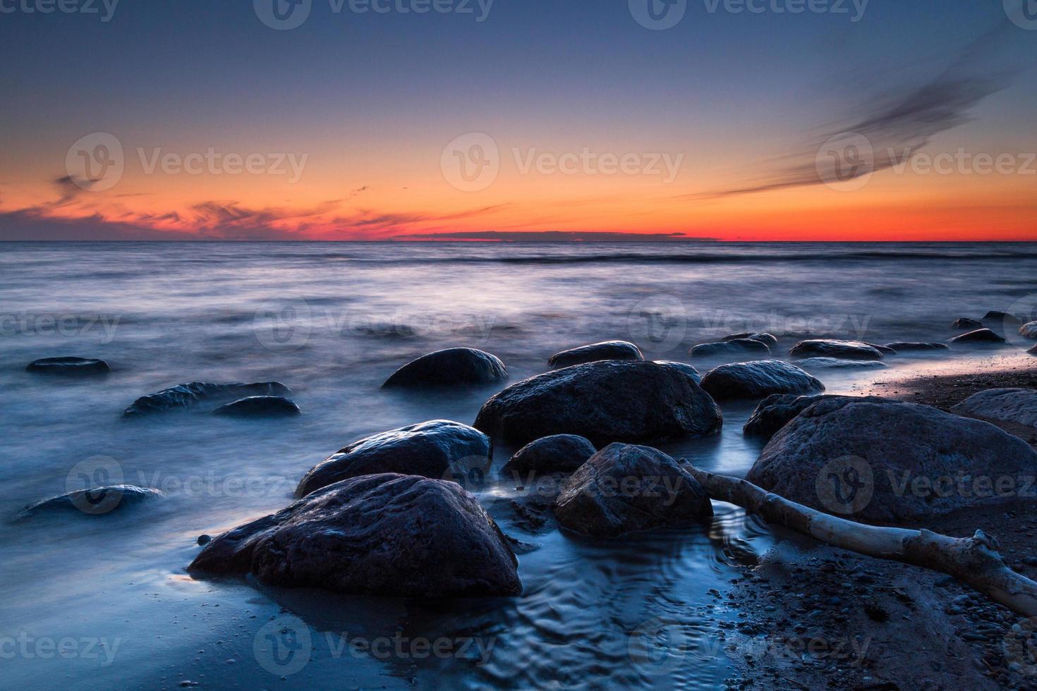 pedras na costa do mar báltico ao pôr do sol foto