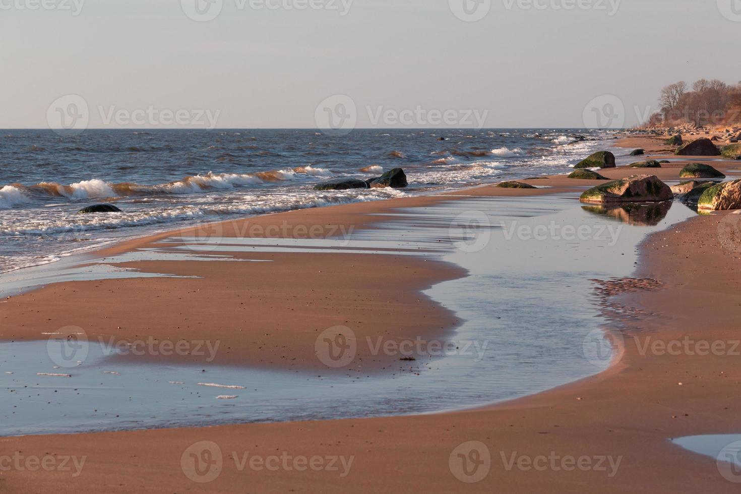 pedras na costa do mar báltico ao pôr do sol foto