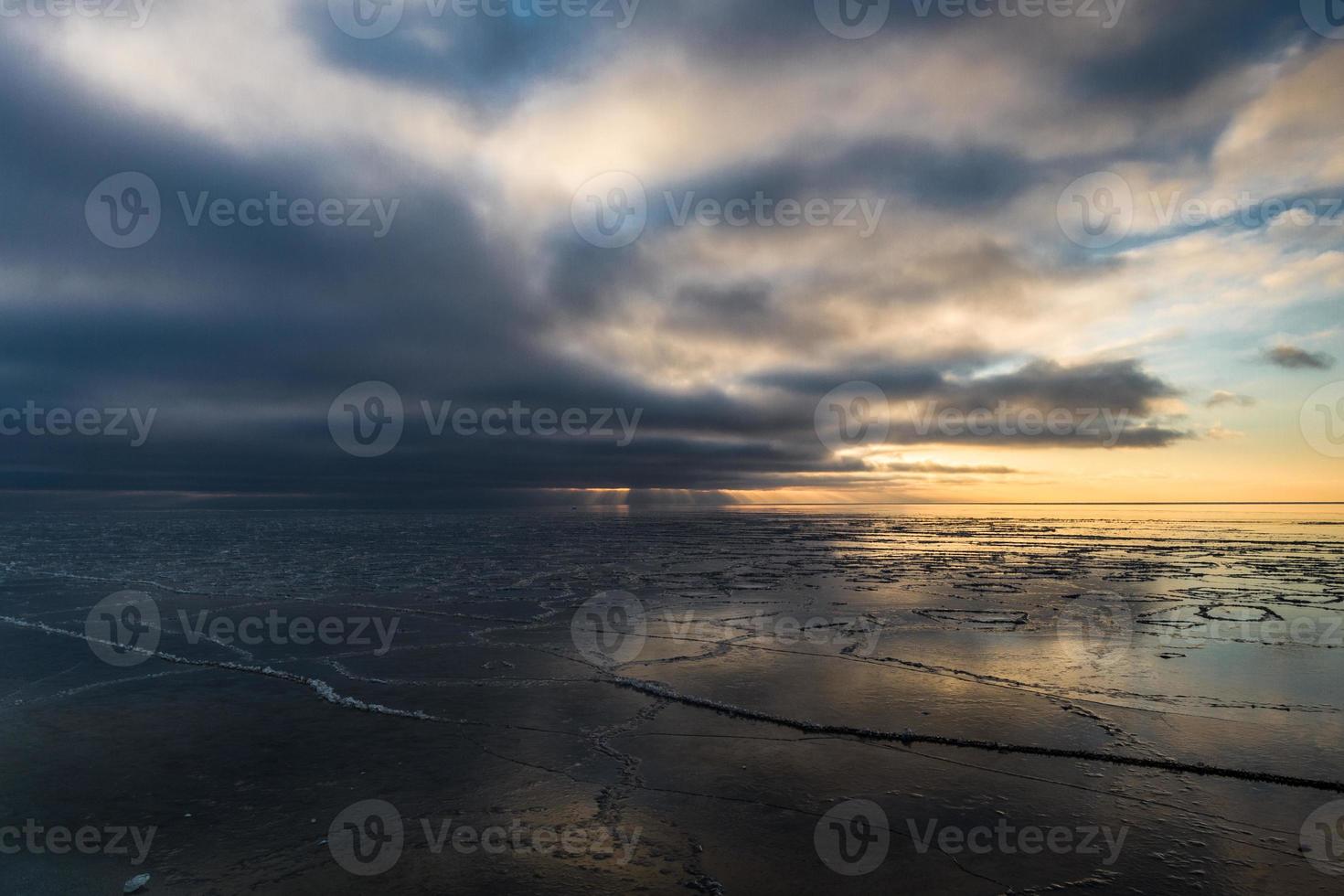 costa do mar báltico com seixos e gelo ao pôr do sol foto