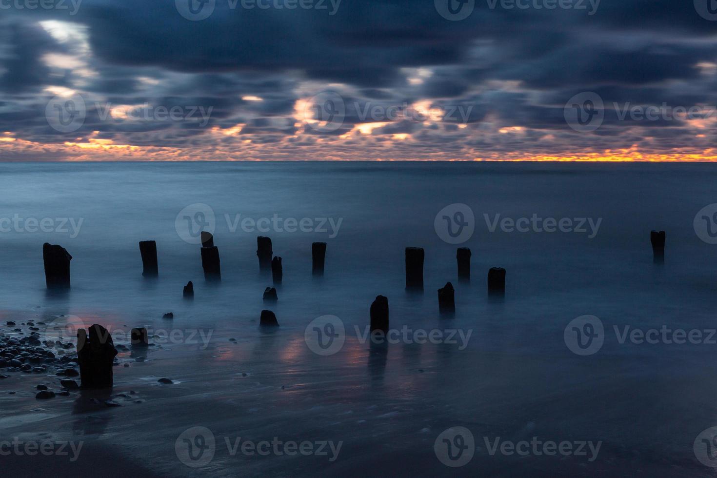 costa do mar báltico com seixos e gelo ao pôr do sol foto