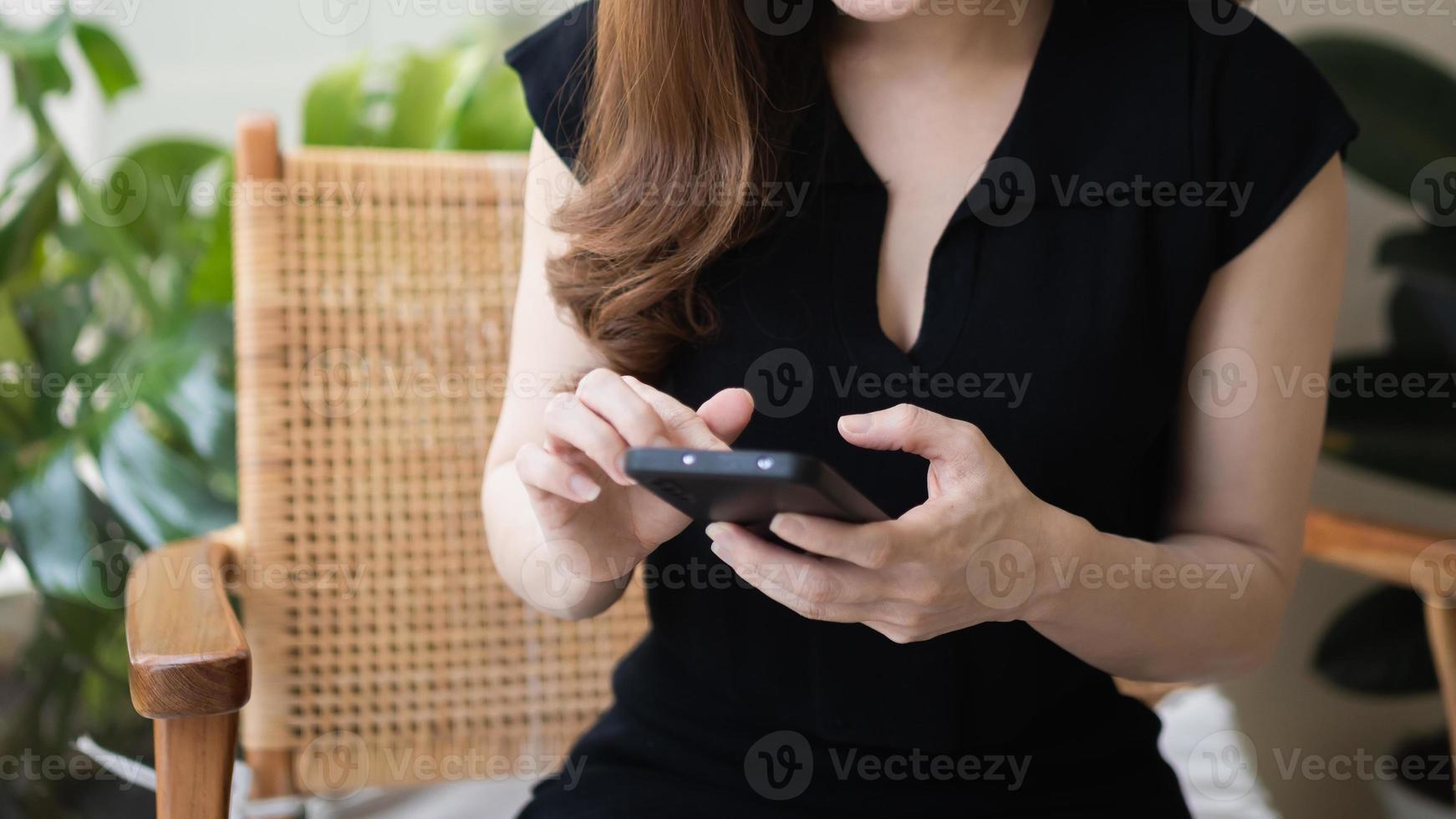 Cortar a foto. mulher trabalhadora segura mensagem de texto do celular, conversa de bate-papo usando a mídia social. a empresária usa o smartphone para navegar na web, ler o e-book, negociar ações. conceito de tecnologia de comunicação foto