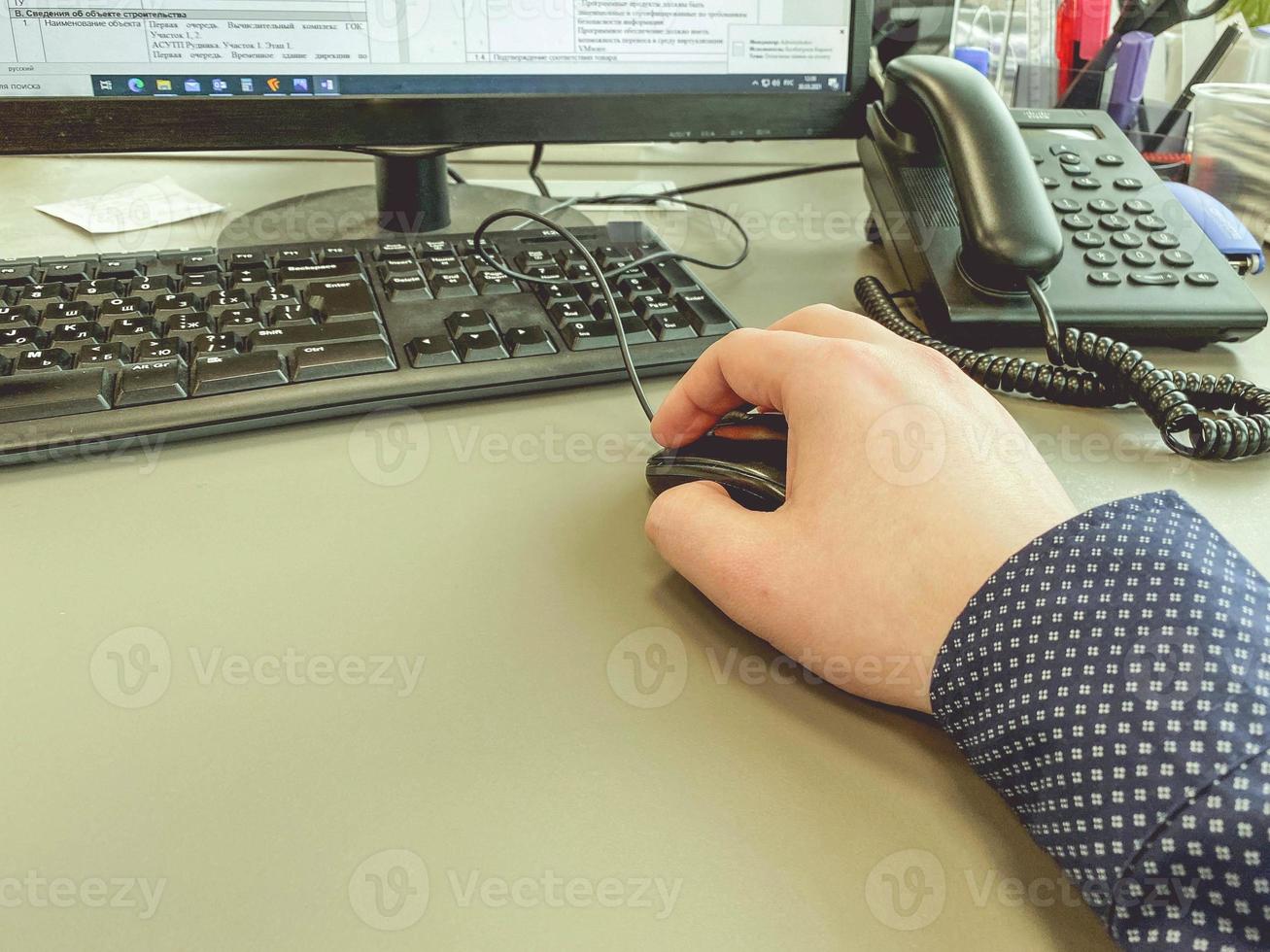 escritório. um homem de camisa azul clica em um mouse. trabalhar no computador. trabalho intelectual. o programador compõe o código para o site foto