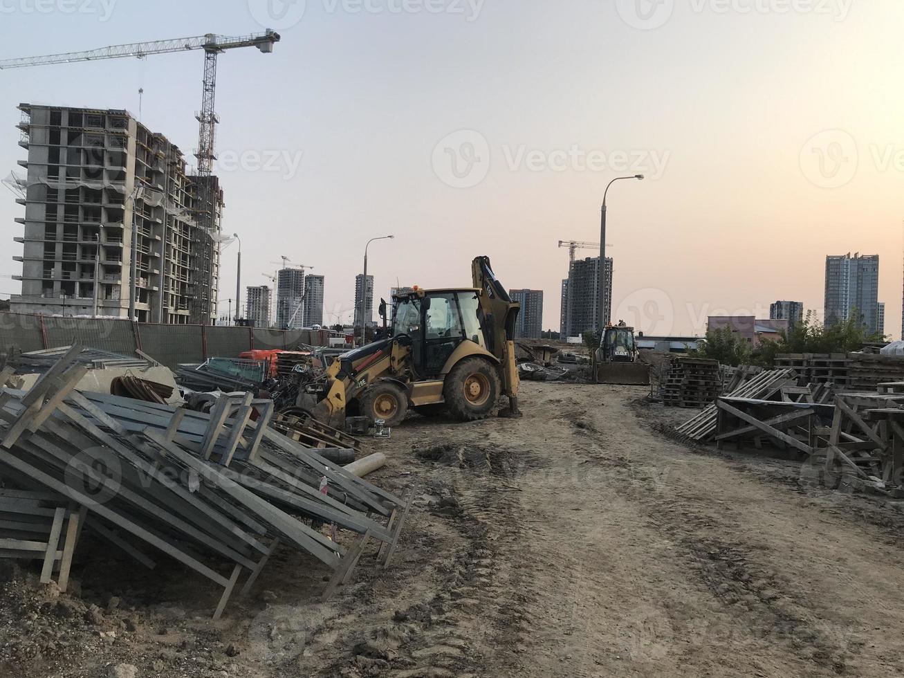 trator carrega restos de construção no canteiro de obras. lixo de concreto, tijolos e outros resíduos de construção. área de descarte de lixo foto