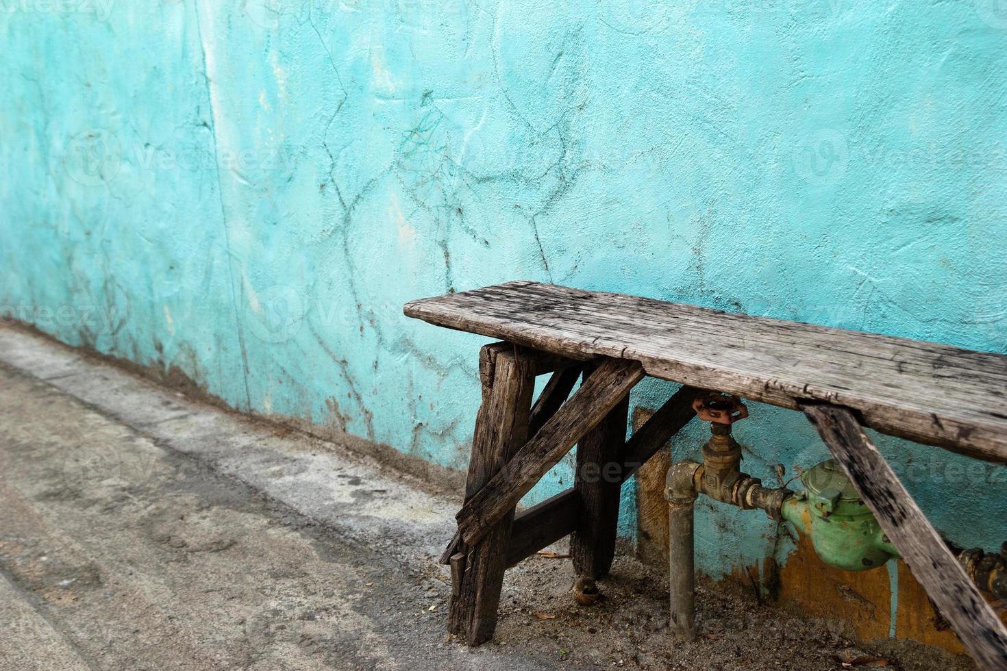 velho banco de madeira perto da velha parede azul e branca rachada. foto