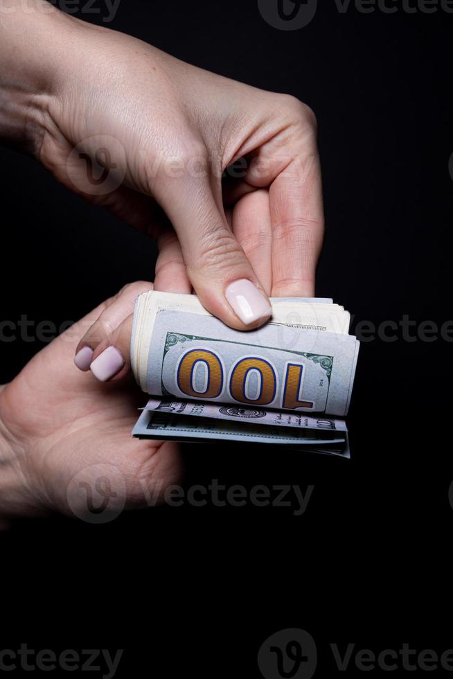 duas mãos com dólares. closeup mão feminina dando dinheiro para algo com isolado em fundo preto, contagem, pagando, compras com dólar, corrupção, contando notas de dólar em preto foto