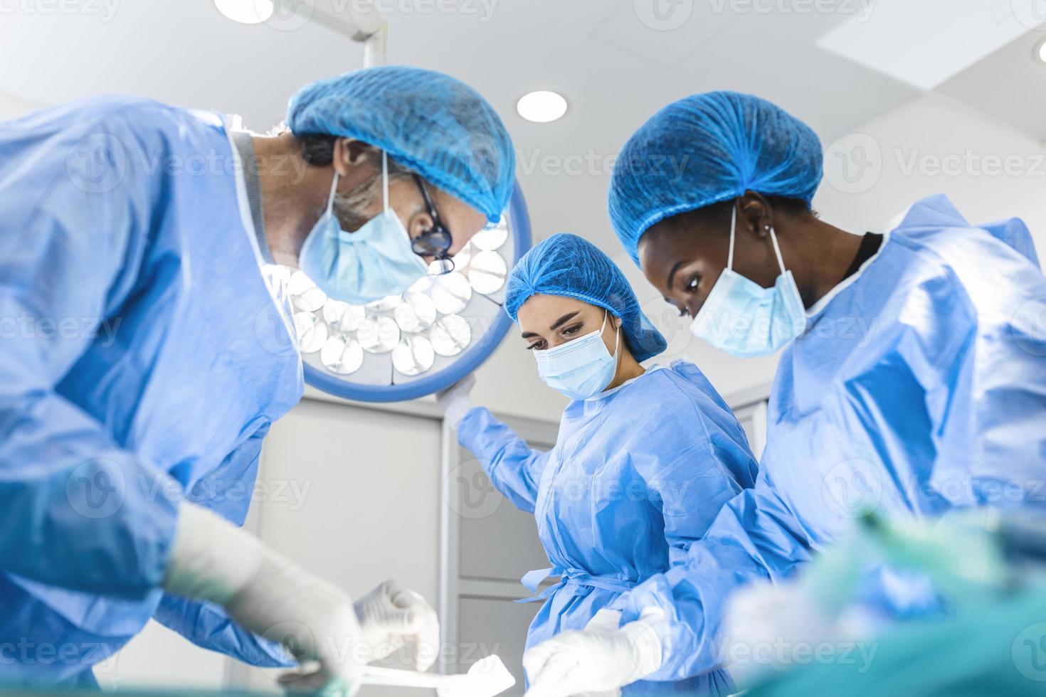 preparação para o início da operação cirúrgica com corte. grupo de cirurgiões no trabalho na sala de operações em tons de azul. equipe médica realizando operação foto