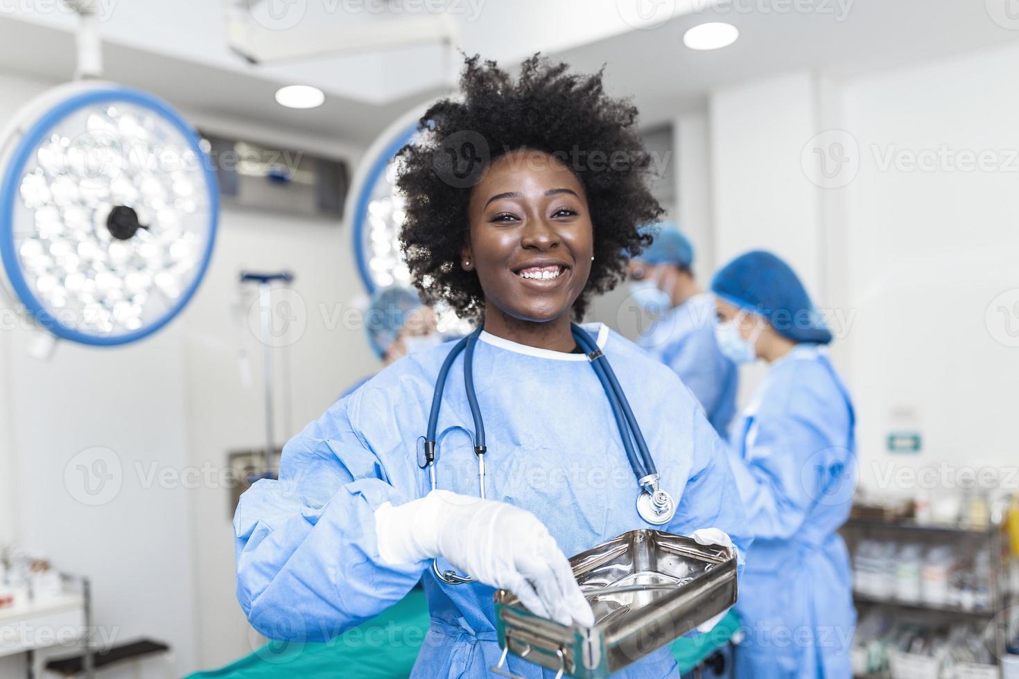 retrato de enfermeira enfermeira cirurgiã ou membro da equipe vestida com bata cirúrgica máscara e rede de cabelo no teatro da sala de cirurgia do hospital fazendo contato visual sorrindo satisfeito feliz olhando para a câmera foto