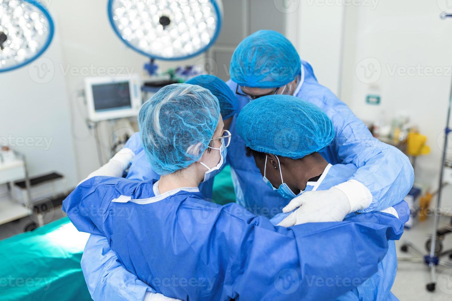 profissionais médicos se abraçando na UTI. médicos e enfermeiras usam macacões de proteção após o tratamento bem-sucedido. eles estão no hospital durante o covid-19. foto