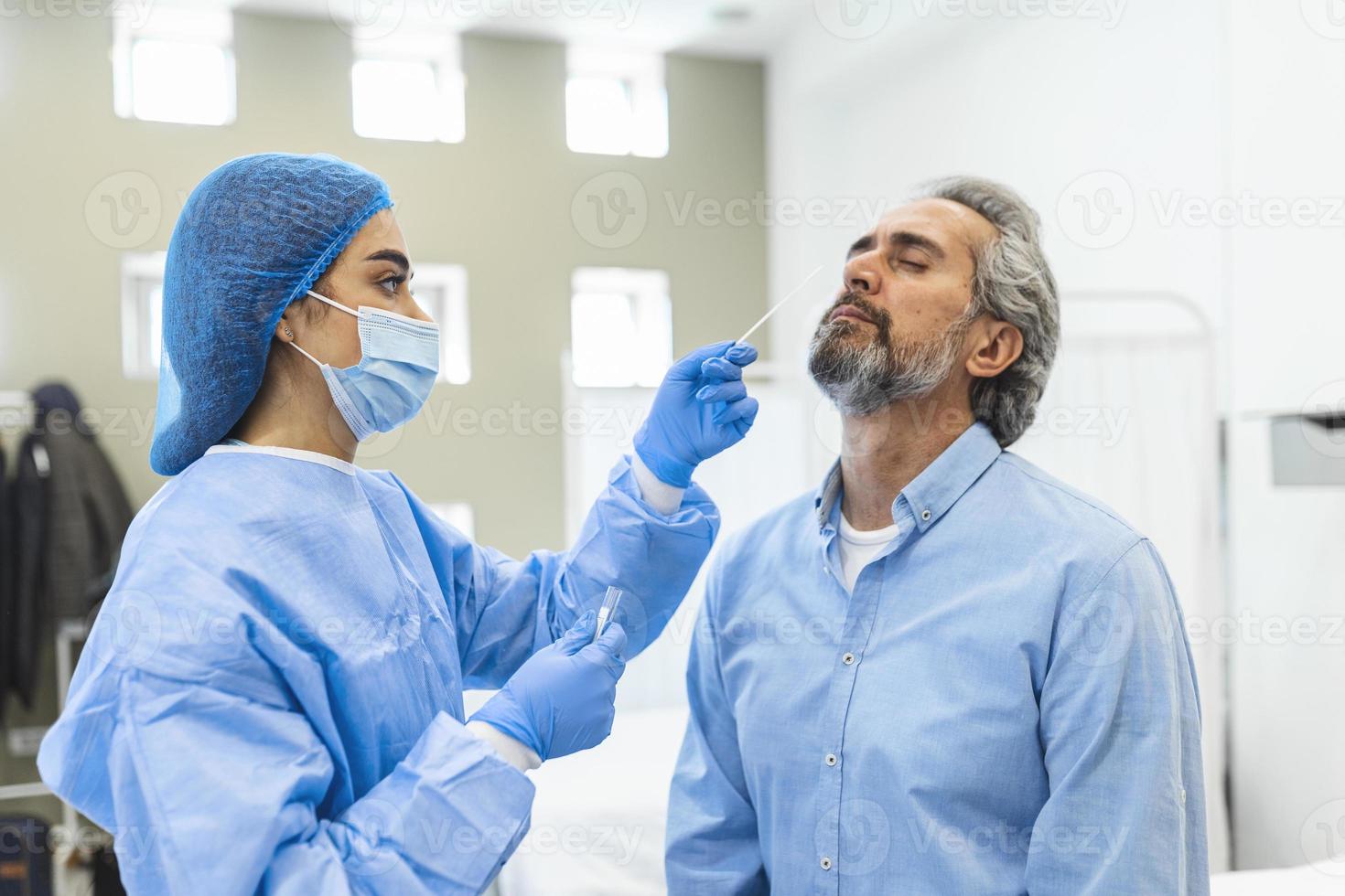 profissional de saúde com equipamento de proteção realiza swab de coronavírus em homem idoso. cotonete nasal para covid-19. foto