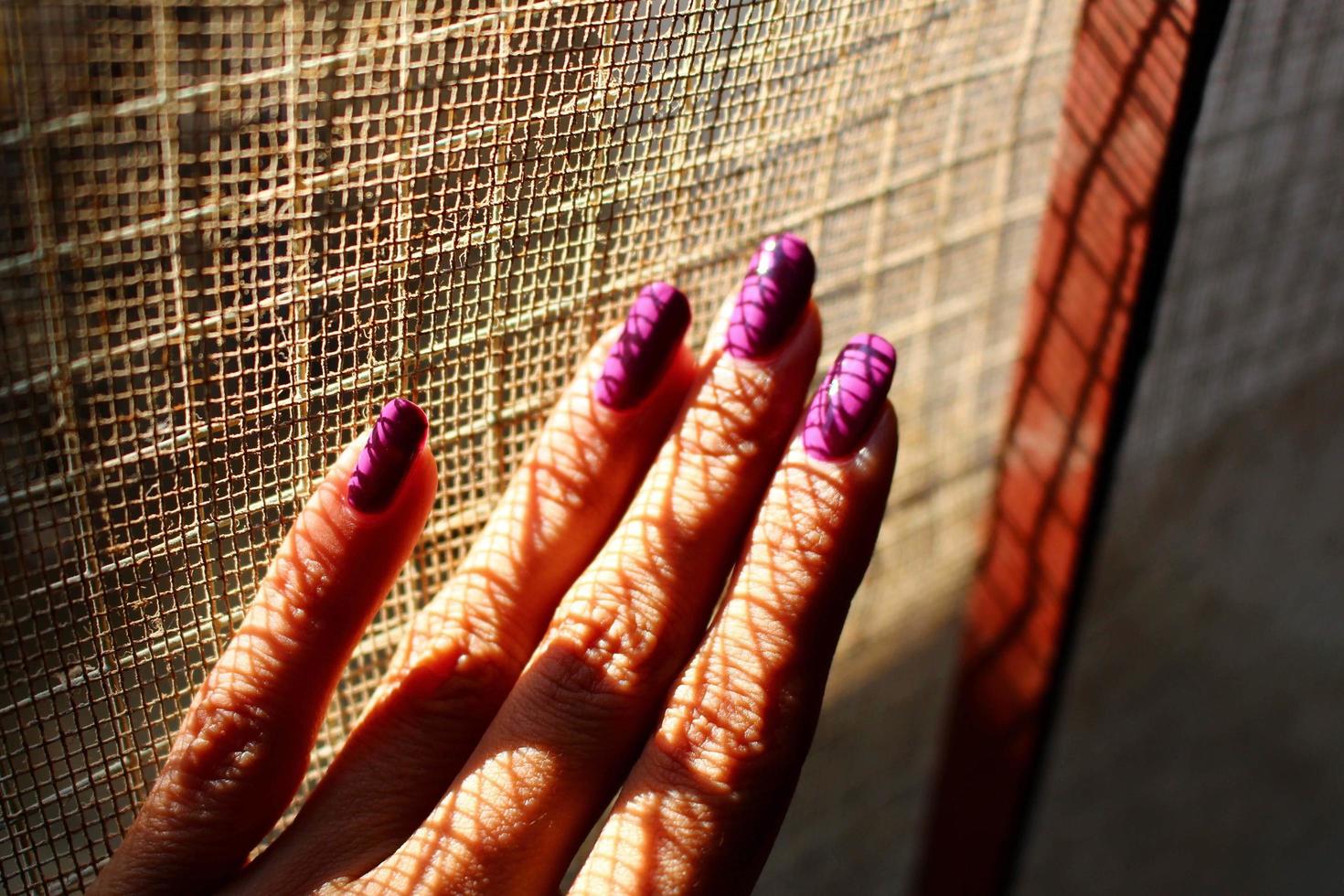 closeup da mão de uma mulher com unhas pintadas à luz do sol foto