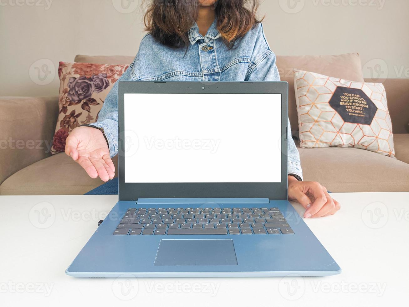 laptop de maquete. mulher asiática mostrando novo modelo de laptop para recomendar conselhos de compra em jaqueta jeans casual na mesa branca foto