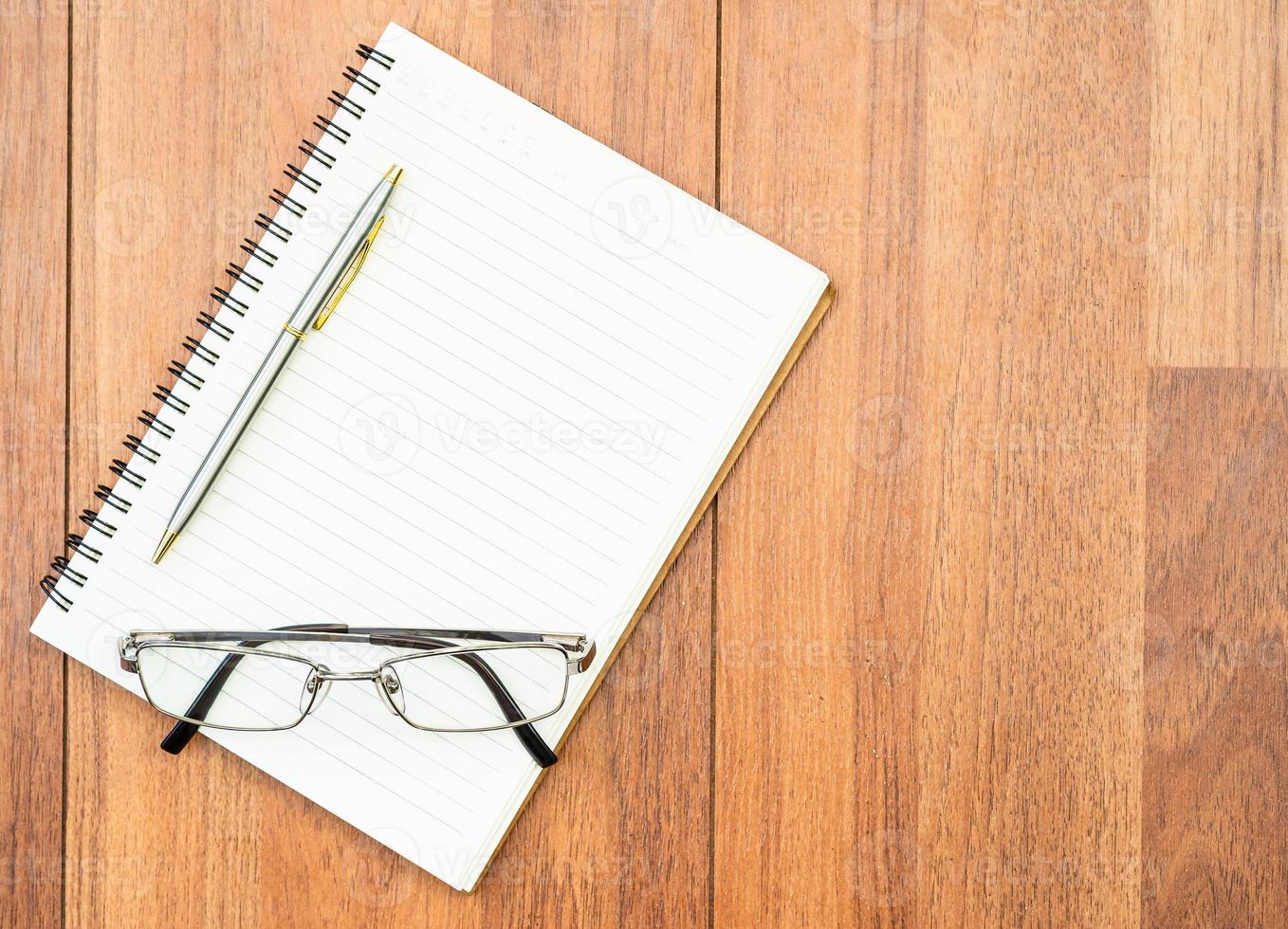 óculos e bloco de notas no deck de madeira com copyspace foto