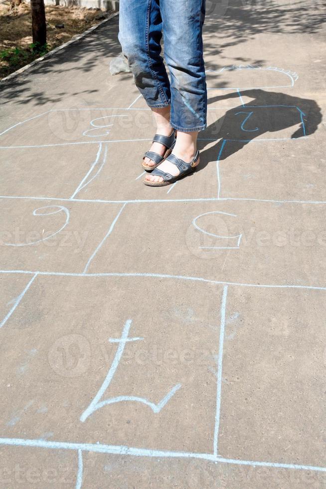 menina brincando de amarelinha no beco urbano foto