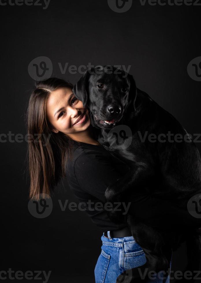 uma garota tem um cachorro labrador retriever nos braços. foto