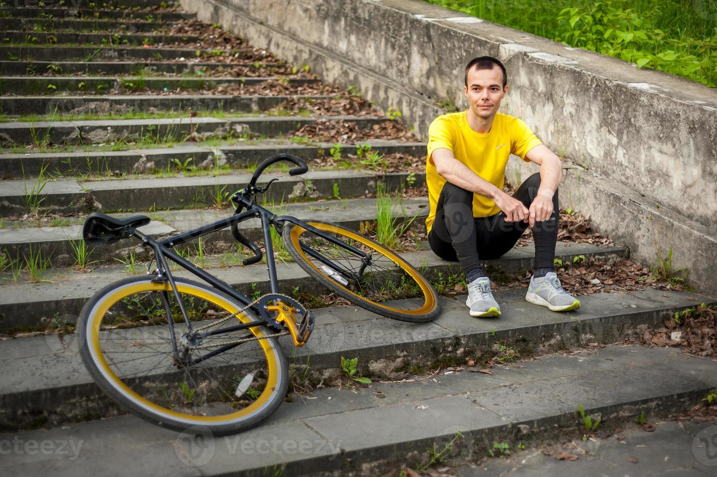 um jovem parou para descansar com sua bicicleta em um parque público. foto
