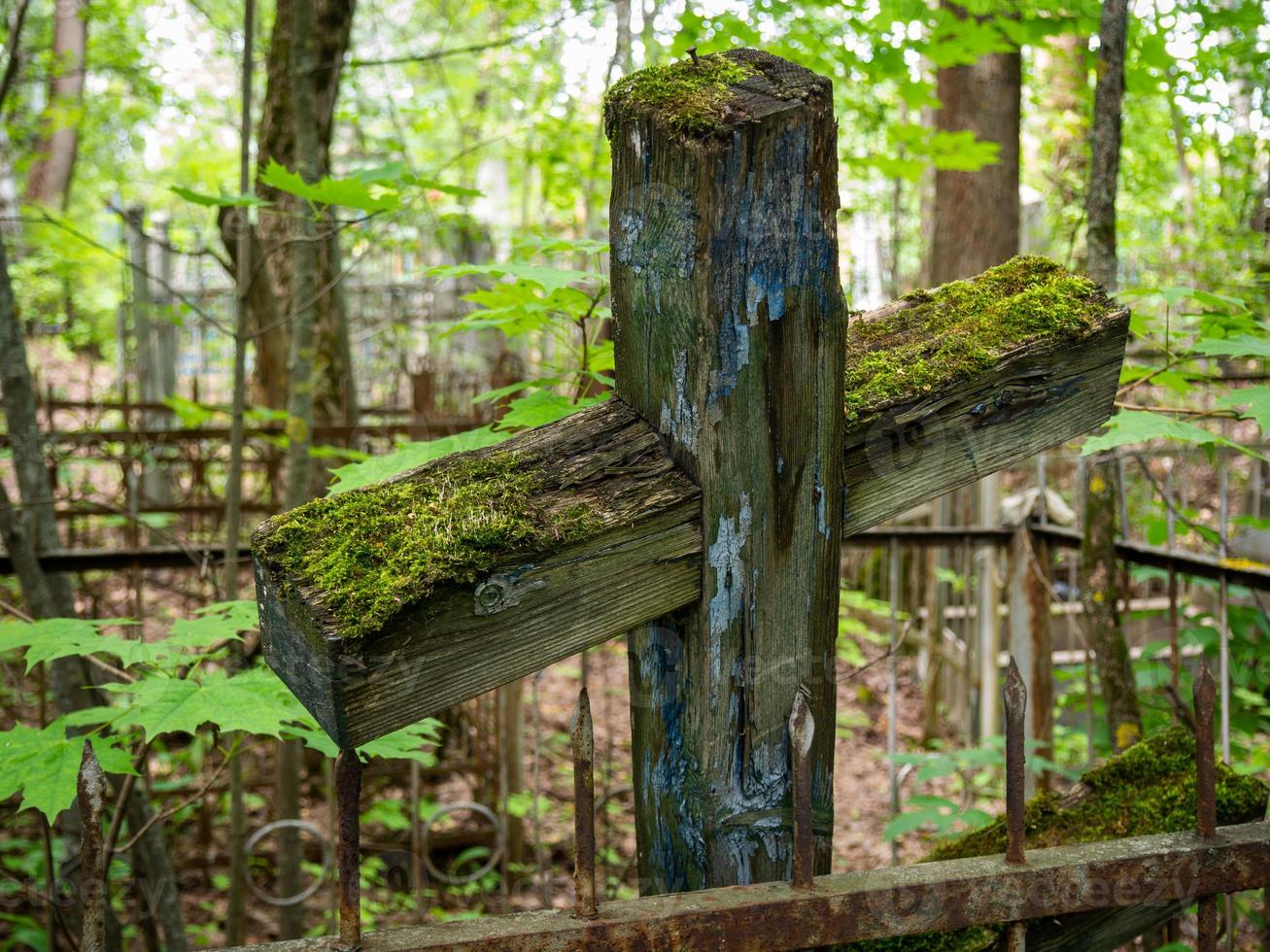 uma velha cruz abandonada coberta de musgo verde. foto