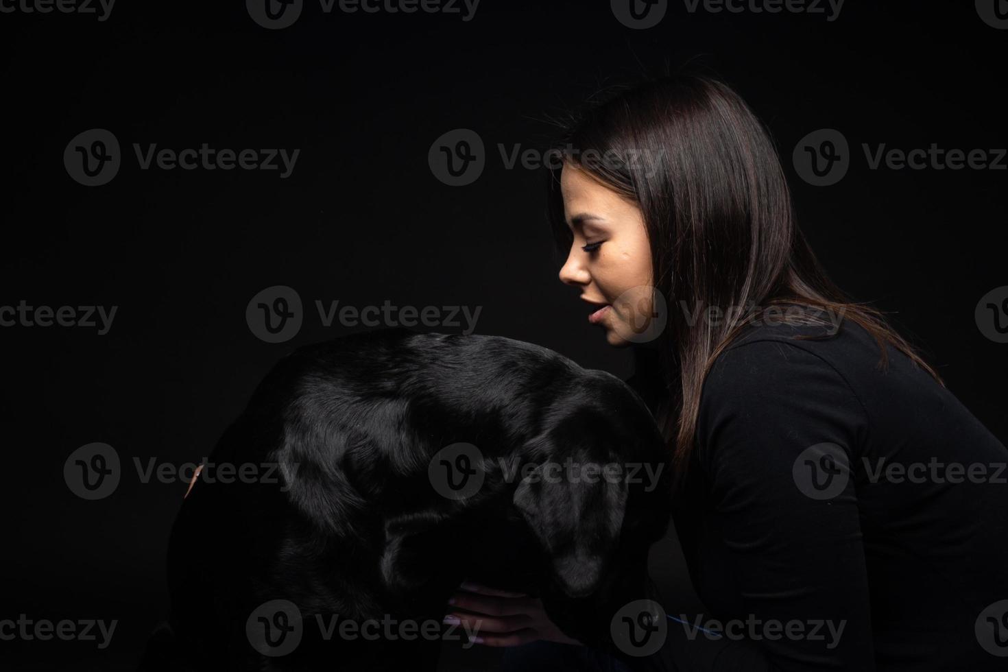 uma garota tem um cachorro labrador retriever nos braços. foto