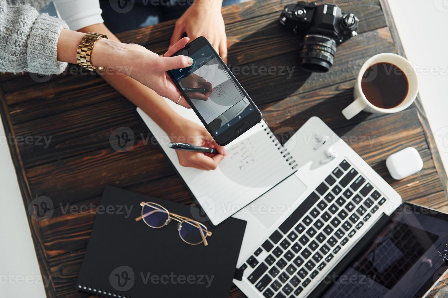 segurando o telefone. jovem freelancer trabalhando dentro de casa no escritório durante o dia. notebook e bloco de notas foto